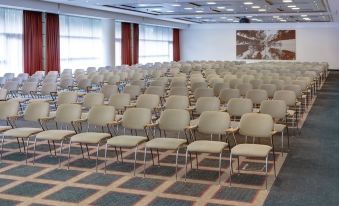 a large conference room with rows of white chairs arranged in an orderly fashion , ready for an event at Steigenberger Airport Hotel Amsterdam