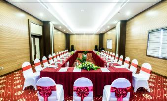 a formal dining room with a long table covered in a red tablecloth , set for a wedding reception at Muong Thanh Grand Hoang Mai - Nghe An