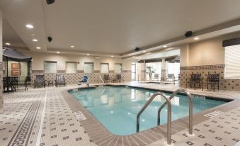 a large swimming pool with a ladder and chairs in an indoor setting , under a ceiling with spotlights at Hilton Garden Inn Columbus/Edinburgh