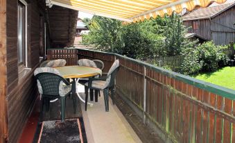 a wooden deck with a dining table , chairs , and an awning providing shade over the outdoor area at Drexler