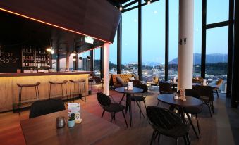 a modern lounge area with large windows , wooden tables , and chairs , overlooking a city skyline at dusk at Arte Hotel Salzburg