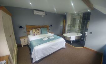 a spacious bedroom with a large bed , a bathtub in the bathroom , and a shower at The Feathers