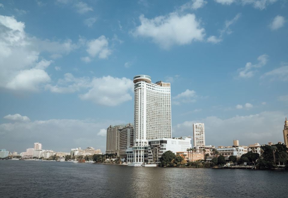 a city skyline with a tall building in the center , surrounded by other buildings and water at Grand Nile Tower