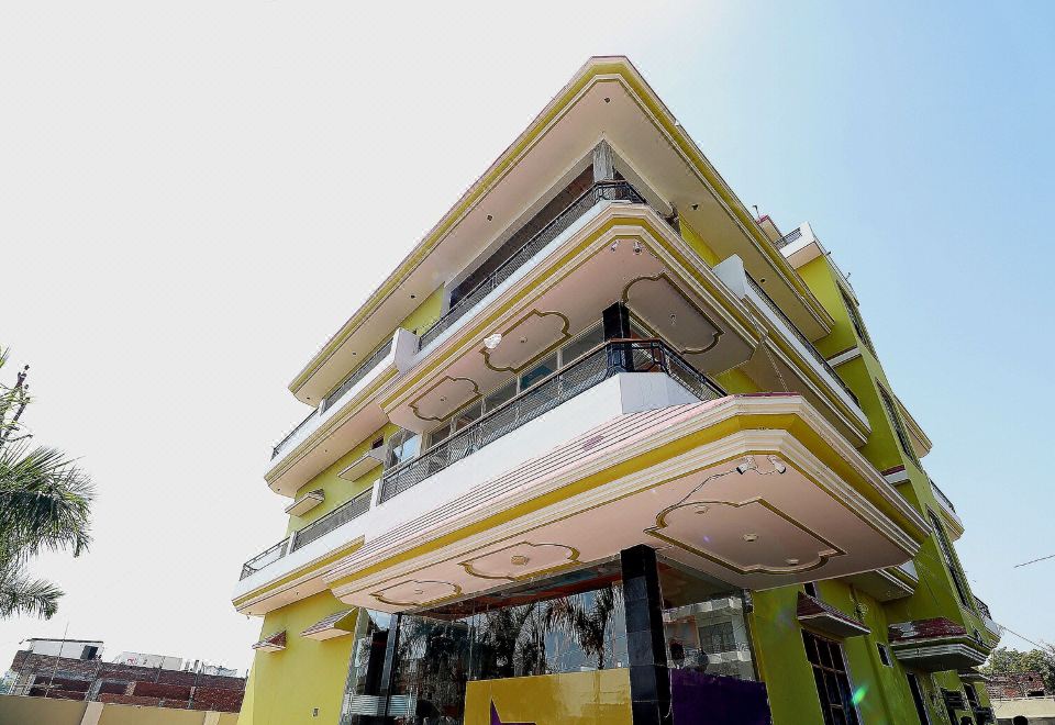 a modern , yellow - colored building with balconies and large windows , standing under a clear blue sky at Collection O 27949 Hotel Kriti Green