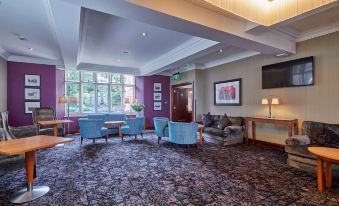 a hotel lobby with a couch , chairs , and a television mounted on the wall at The Abbey