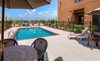 a large swimming pool is surrounded by lounge chairs and an umbrella , with a building in the background at Best Western Hotel Rebstock