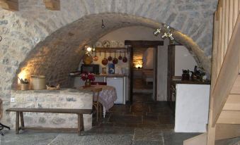 a dining room with a table and chairs , as well as a kitchen area with an arched doorway at La Bergerie
