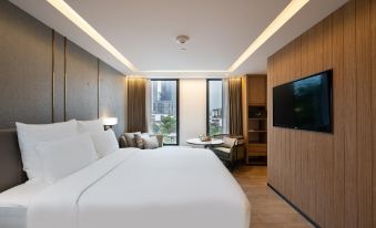 In the background, there is a bedroom with two beds and an attached bathroom, as well as side tables at HOMM Sukhumvit34 Bangkok - a brand of Banyan Group