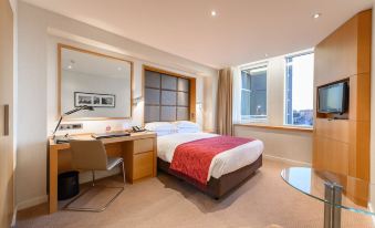 A bedroom with large windows, a bed, and a desk in the middle is also equipped at Royal Garden Hotel