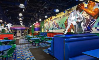 a modern bar with a large mural on the wall , blue couches , and green tables at Disney's All-Star Sports Resort