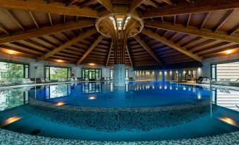 an indoor swimming pool surrounded by wooden ceiling beams , with a person standing in the water at Castilla Termal Solares