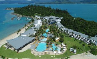 aerial view of a resort with multiple buildings , a pool , and a beach area near the water at Daydream Island Resort