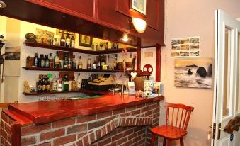 a bar with a brick wall and a red counter , surrounded by bottles of alcohol at Acorns Guest House