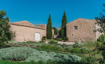 a stone building with a white door , surrounded by lush greenery and blue skies , under a clear blue sky at Baglio Occhipinti