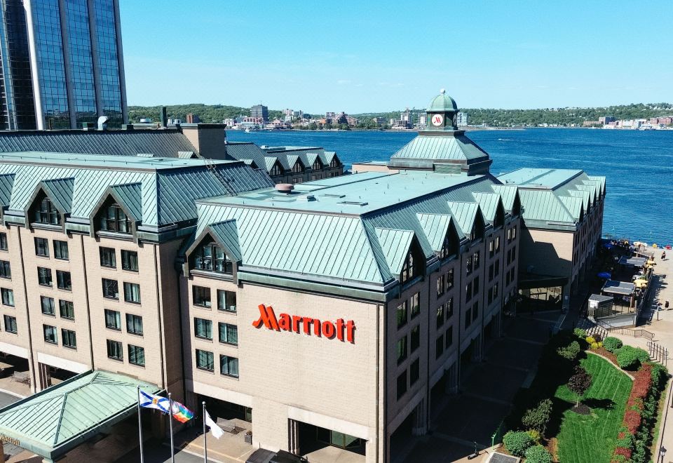 a large hotel building with a marriott sign on the front , surrounded by water and mountains in the background at Halifax Marriott Harbourfront Hotel