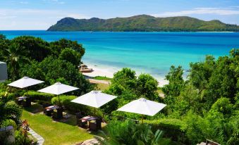 a beautiful beach scene with multiple umbrellas set up on the sand , providing shade for beachgoers at Raffles Seychelles