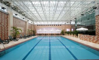 The hotel features an indoor swimming pool with a spacious roof adorned with white and blue tiles at Holiday Inn Shanghai Pudong