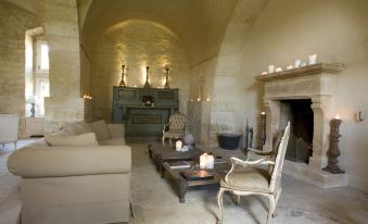 a living room with stone walls , a fireplace , and a couch , lit by candles on the coffee table at Castello Camemi