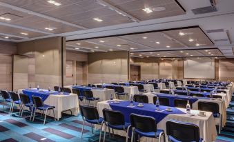 a large conference room with rows of chairs arranged in a semicircle , and a podium at the front of the room at Cosmos Pacifico Hotel