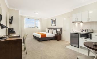 a modern hotel room with a bed , desk , and kitchenette , all equipped with amenities such as microwave , refrigerator , and dining table at Quest Breakfast Creek