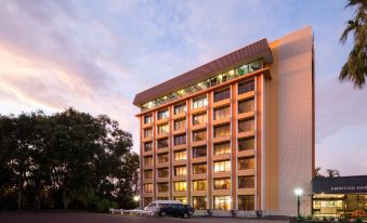 a large building with many windows is lit up at night , surrounded by trees and parked cars at Frontier Hotel Darwin