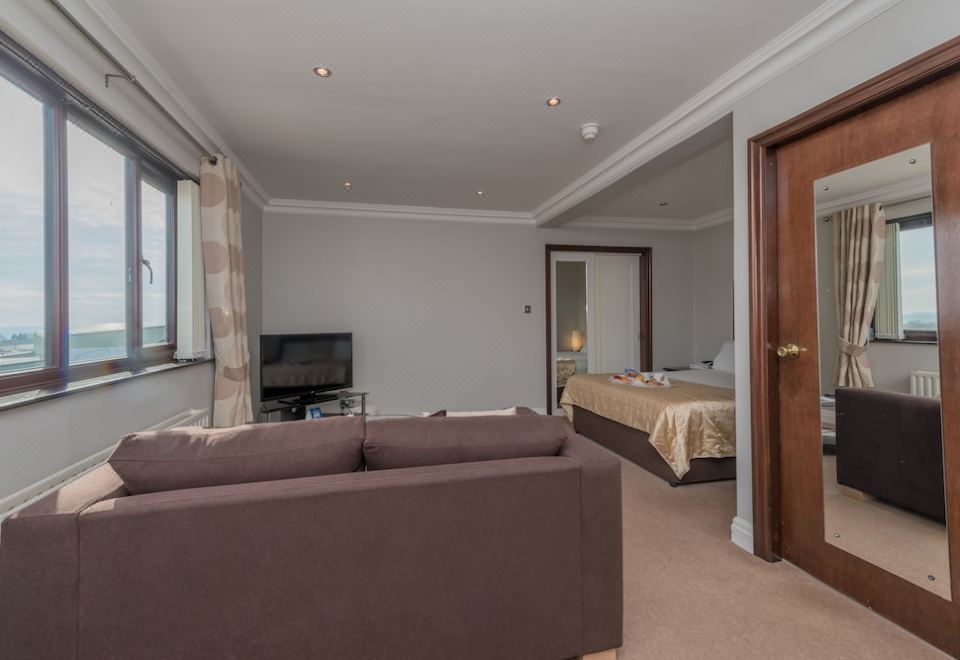 a living room with a brown couch , television , and a door leading to a bedroom at Best Western Bradford Guide Post Hotel