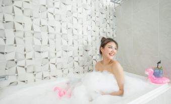 a woman is sitting in a bathtub filled with bubbles , enjoying a bubble bath and posing for a picture at Hotel Cham Cham - Taipei