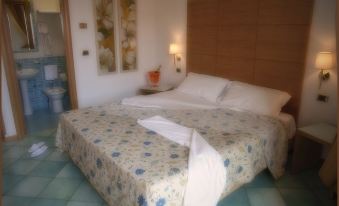a large bed with a floral comforter and white pillows is in a room with a wooden headboard at City Hotel