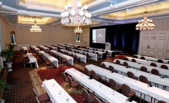 a large , empty conference room with multiple rows of chairs and a projector screen at the front at The Saint Paul Hotel