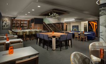 a modern bar with wooden tables , chairs , and stools , as well as a dining area with wine glasses at Hyatt Centric Arlington