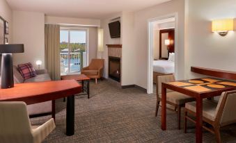 a hotel room with a king - sized bed , a dining table , a television , and a fireplace at Residence Inn Gravenhurst Muskoka Wharf
