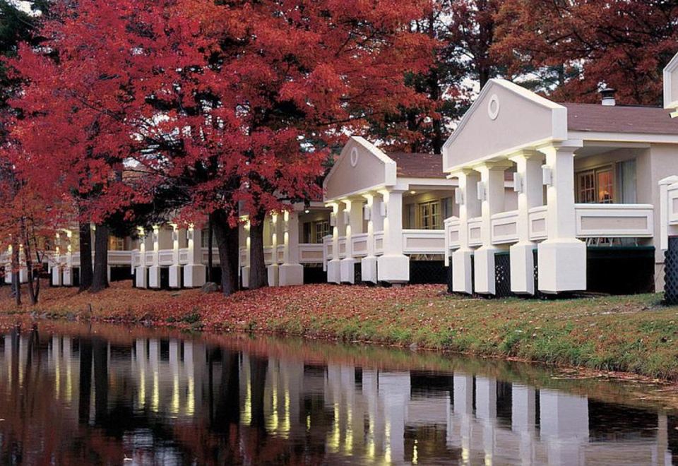a row of white houses along a river with red trees in the background , creating a picturesque scene at Paradise Stream Resort