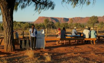 a group of people gathered around a picnic table in a desert landscape , enjoying the outdoors at Discovery Resorts - Kings Canyon