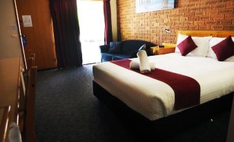 a hotel room with a comfortable bed , a couch , and a tv . also a dining table in the room at Kerang Motel