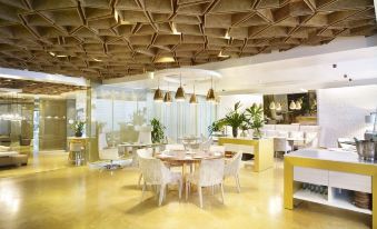 a modern restaurant with yellow and white furniture , pendant lights , and a wooden ceiling decoration at Bog Hotel