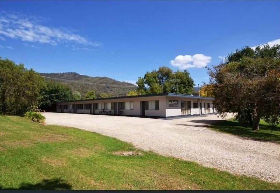 a large , modern building with a long driveway and a clear blue sky in the background at Mount Beauty Motor Inn