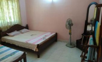a bedroom with two beds , a fan , and a table , all set against pink walls at Rivers Edge