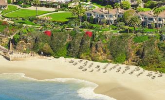 aerial view of a beach resort with multiple buildings , umbrellas , and palm trees surrounding the area at Montage Laguna Beach