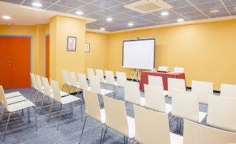 a conference room with white chairs arranged in rows and a projector screen on the wall at Hotel Gran Via