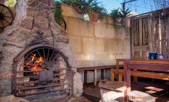 a stone oven with a fire pit inside , surrounded by potted plants and chairs , set against a backdrop of a building at Prince of Wales Hotel Gulgong