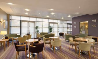 a large , modern lounge area with several chairs and couches arranged in a seated position at Ramada Plaza by Wyndham Wrexham