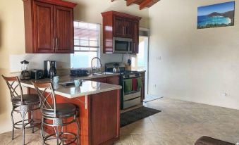 a kitchen with wooden cabinets , a dining table , and a living room area with a couch at Ocean View Villas