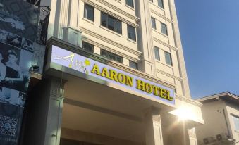A building with the entrance to an art deco-style hotel in front and another sign at Aaron Vientiane Hotel