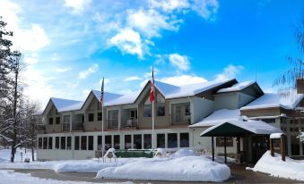 a large , white building with flags flying in front of it , surrounded by snow and blue sky at The Deers Head Inn Tavern