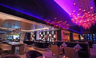 a modern bar with purple lighting , black walls , and various seating arrangements , including couches and chairs at Park Hyatt Doha