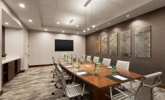a conference room with a large wooden table , white chairs , and green bottles on the table at DoubleTree by Hilton Hartford - Bradley Airport