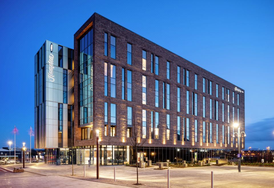 a large brick building with many windows and a glass facade is lit up at night at Hampton by Hilton Stockton on Tees