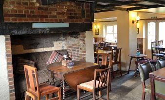 a cozy restaurant with wooden furniture , brick walls , and a brick fireplace , providing a comfortable atmosphere for patrons at The Bowl Inn