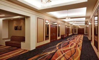 a long , carpeted hallway with multiple doors and a mirror on the right side , leading to an office area at Hilton Chicago/Oak Lawn