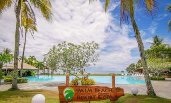 a sign for palm beach resort & spa is shown in front of a pool and palm trees at Palm Beach Resort & Spa